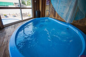 Una amplia piscina cubierta con un muelle de madera alrededor, vistas al exterior y un cartel de 'No Fumar' en la pared.