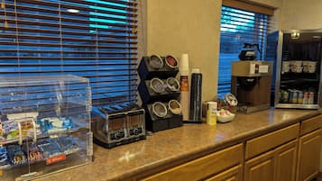 A hotel breakfast area with a coffee machine, a variety of food containers, and a selection of snacks.