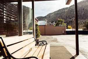 Un banco de madera frente a un edificio, con vistas a un paisaje montañoso.