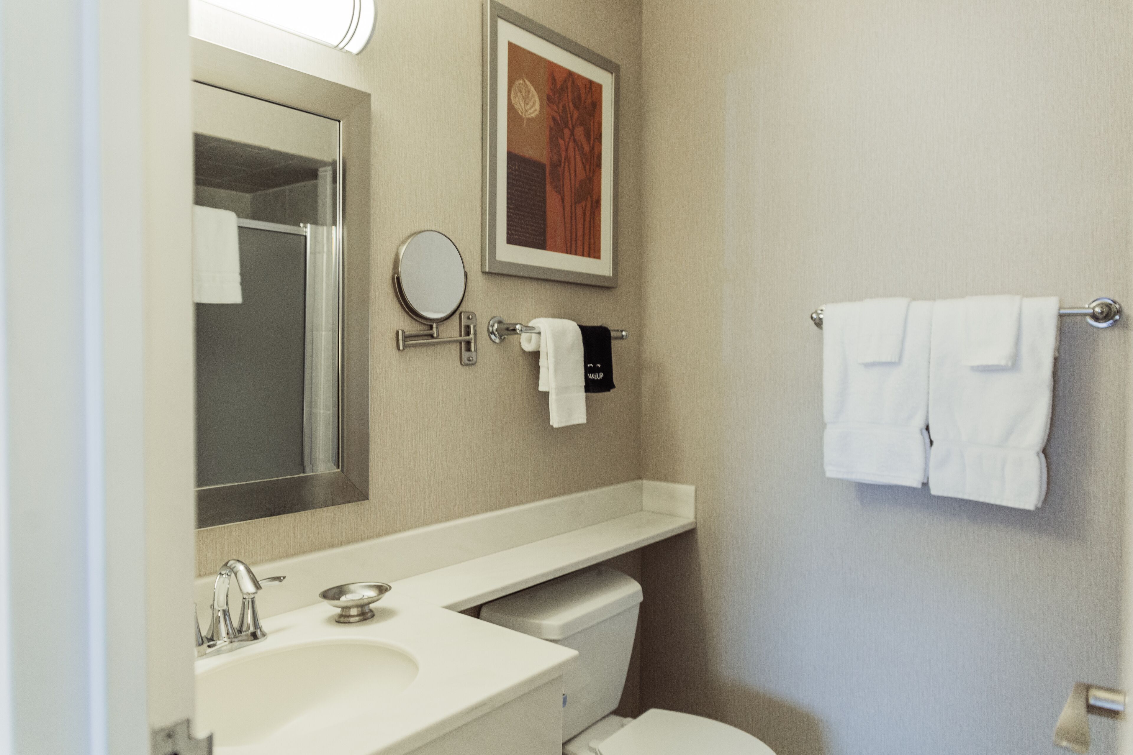 A bathroom with a sink, mirror, toilet, and towel rack.