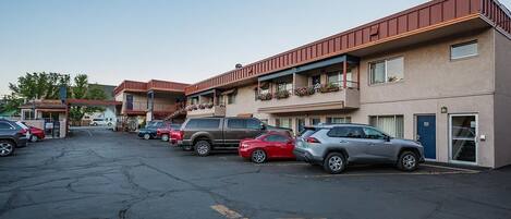Un estacionamiento con varios coches aparcados frente a un motel de varias plantas y balcones.