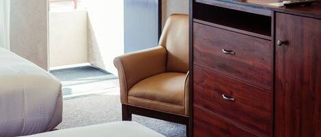 A hotel room with a bed, a desk with a lamp, a chair, and a television.