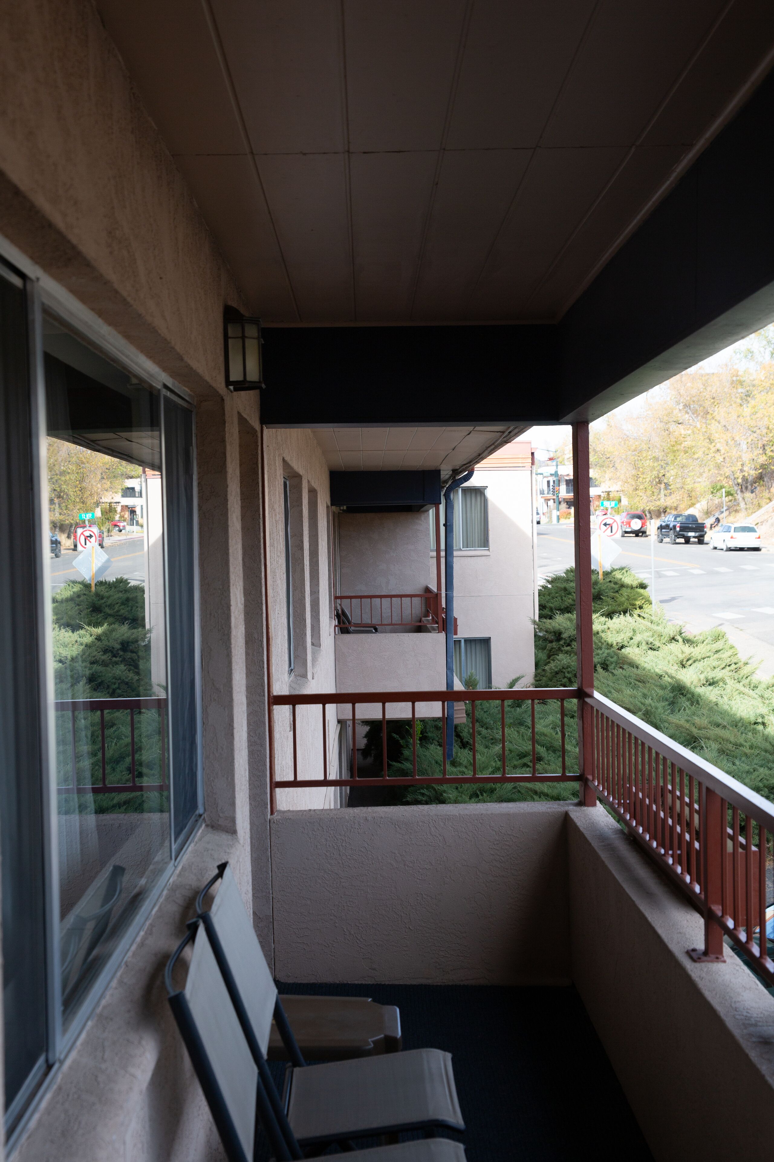 A balcony with a view of a street and parked cars.