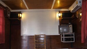 A room with a wooden ceiling, a television on a stand, a ladder, and a couch. - Cowboy Farm Resort Pattaya (Bang Lamung)