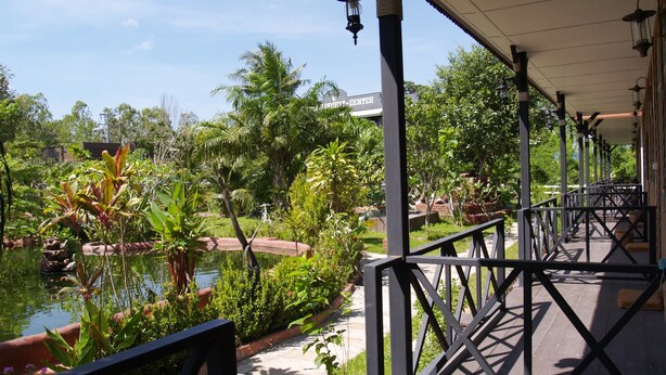 A covered outdoor area with a pool, surrounded by lush greenery and a clear sky. - Cowboy Farm Resort Pattaya (Bang Lamung)