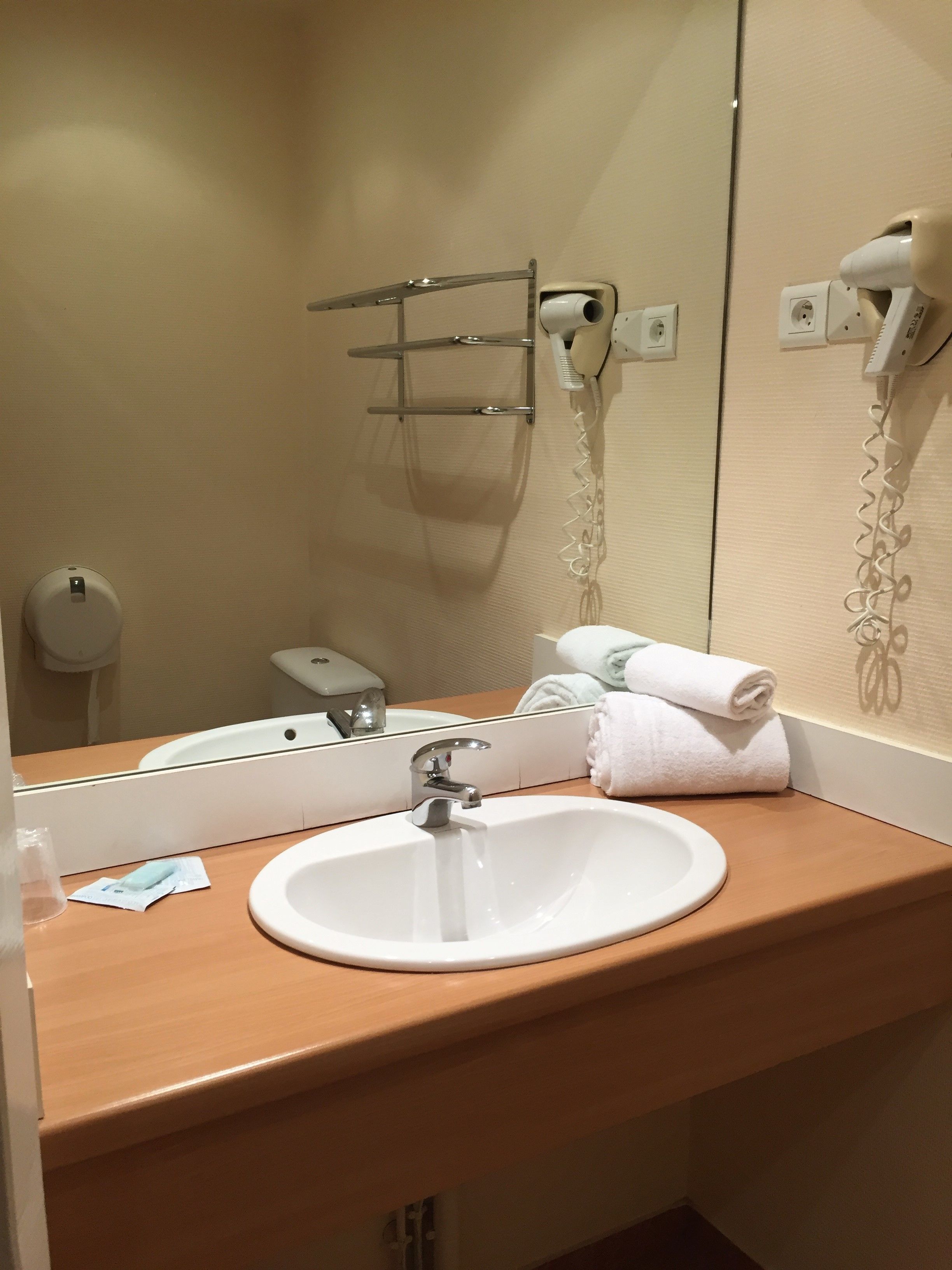 A bathroom with a white sink, a mirror, a towel rack, and a hairdryer.