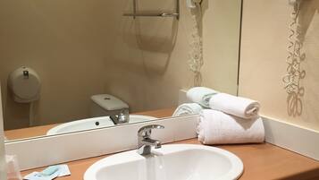 A bathroom with a white sink, a mirror, a towel rack, and a hairdryer.