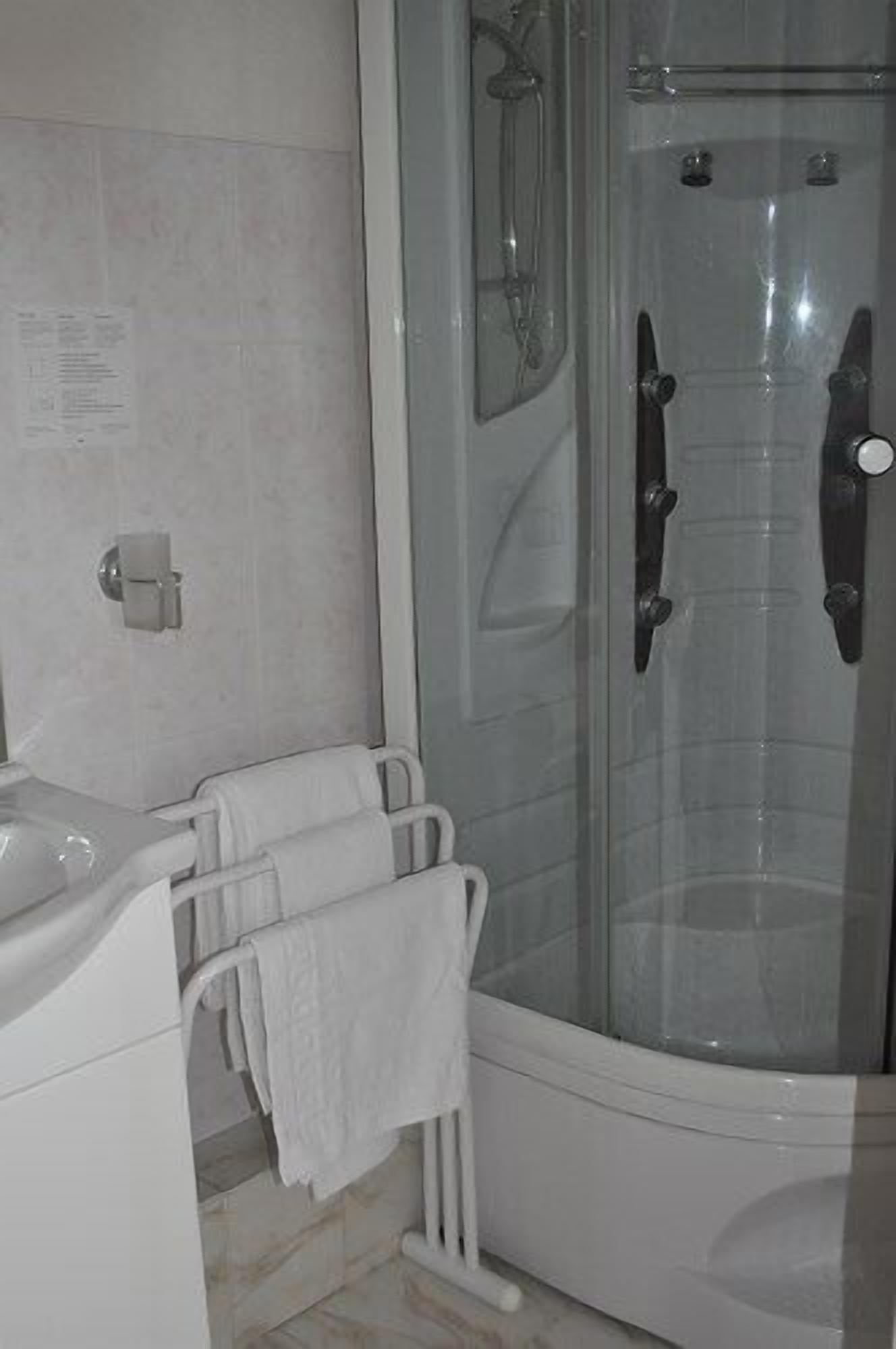 Ein Badezimmer mit einer gläsernen Duschkabine, einem weißen Waschbecken und einem Handtuchhalter.