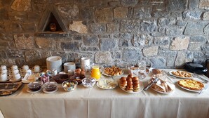 Un bufé de desayuno con diversos alimentos y utensilios sobre una mesa frente a una pared de piedra.