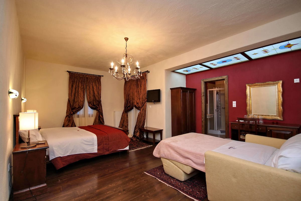 Une chambre d’hôtel avec deux lits, un lustre, une télévision et un miroir.
