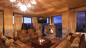 Una sala de estar acogedora con chimenea de piedra, asientos cómodos y un amplio ventanal con vistas panorámicas.