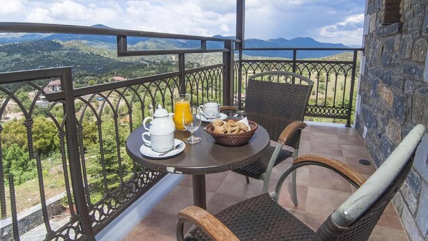 Un balcón con una mesa dispuesta para el desayuno, que incluye una jarra de zumo de naranja, una taza y una cesta de pan.