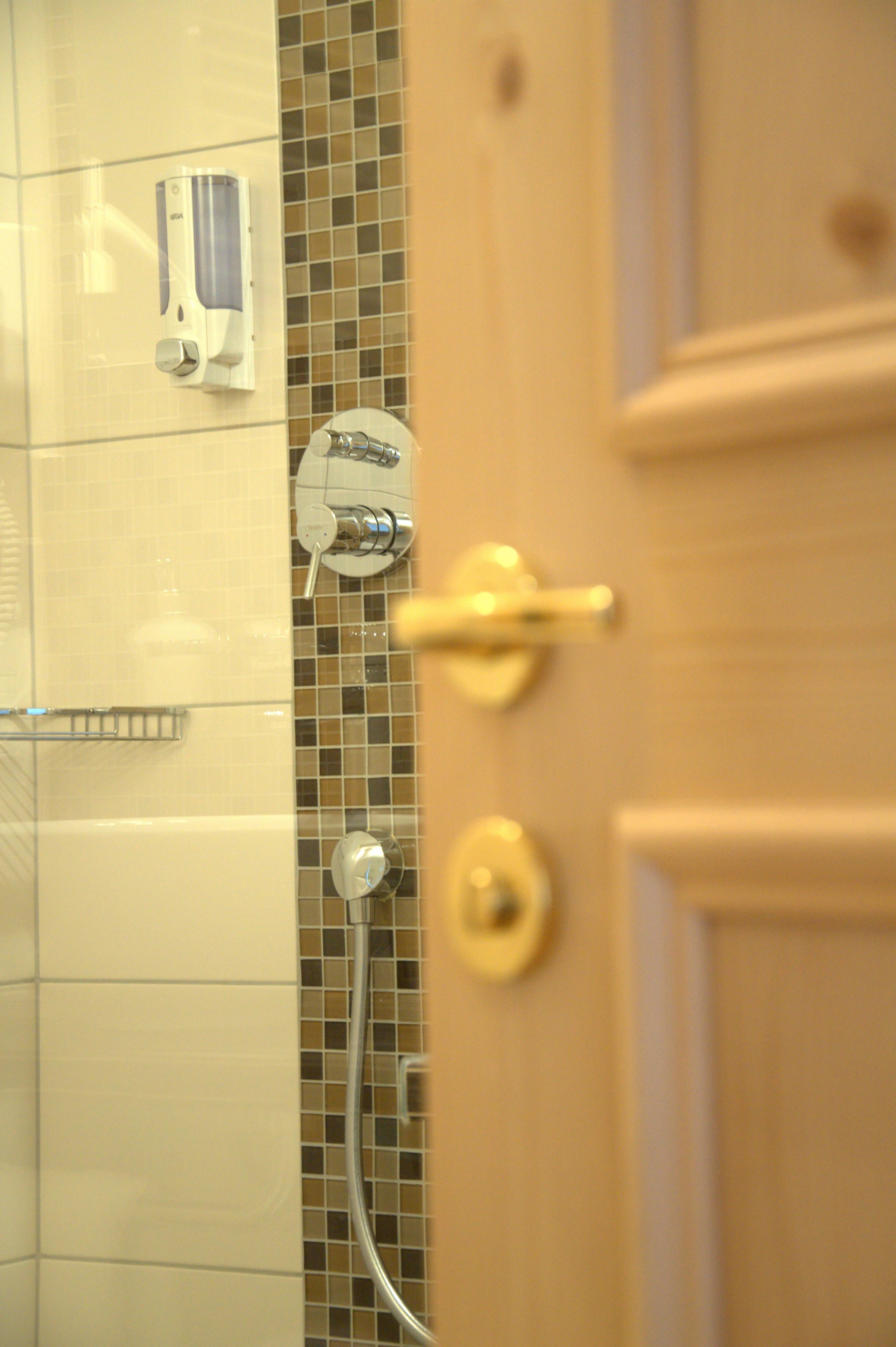 A bathroom with a shower, a hand dryer, and a towel rack.
