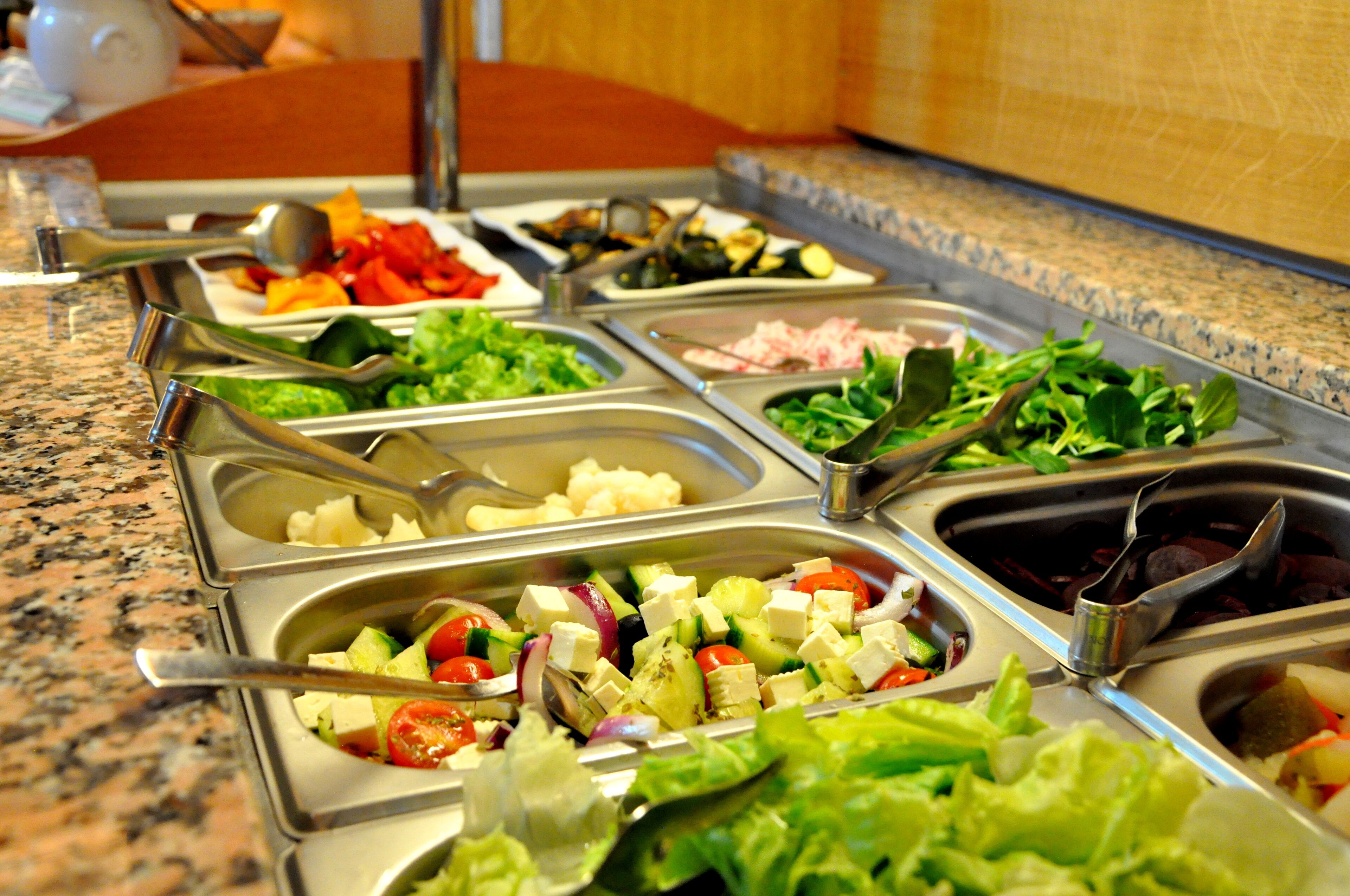 A buffet with various food options including salads, cheeses, and meats.