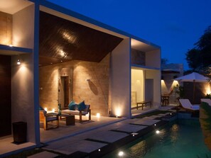A modern house with a swimming pool, outdoor seating, and a well-lit interior. - Villa Scena (Nusa Dua)