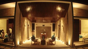 Un hall d’hôtel moderne doté d’un plafond incurvé, d’un espace salon et d’un comptoir d’accueil.