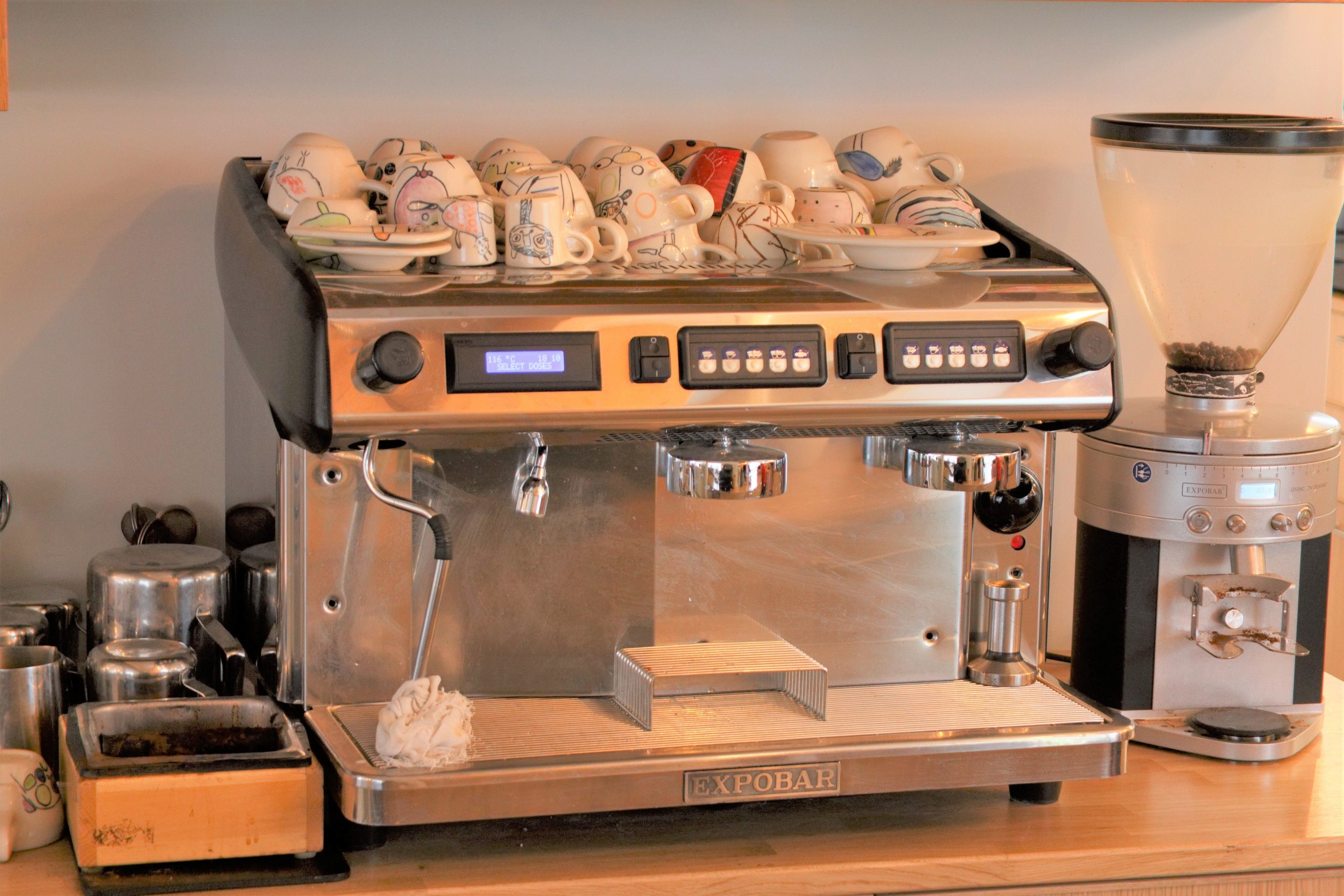 A commercial espresso machine with a digital display, a milk frother, and a grinder.