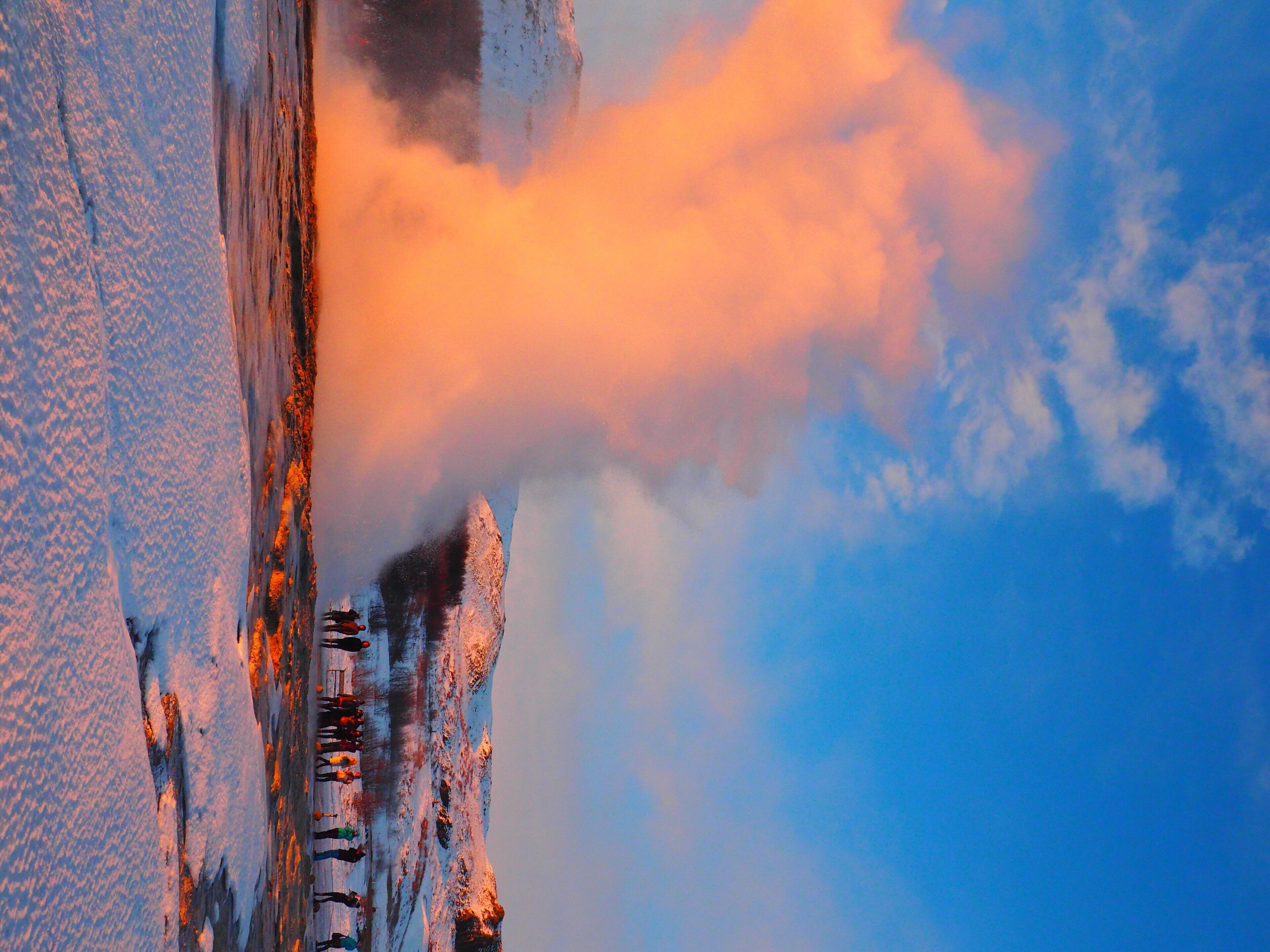 A snow-covered mountain with a clear sky and a few clouds.