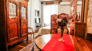 A traditional room with a wooden dining table, a red table runner, a chandelier, and a large mirror. - Le Petit Tertre (Dijon)