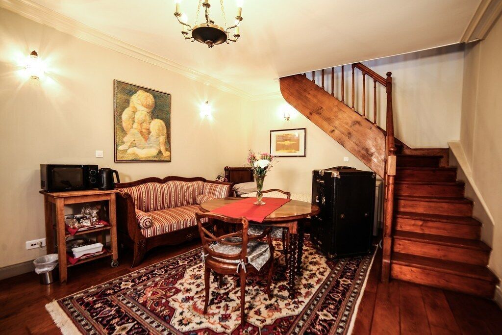 Un salon chaleureux avec un escalier en bois, un canapé à motifs, une table à manger avec des chaises et un grand tableau accroché au mur.