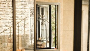 A window with a view of a stone wall and a metal railing. - Le Petit Tertre (Dijon)