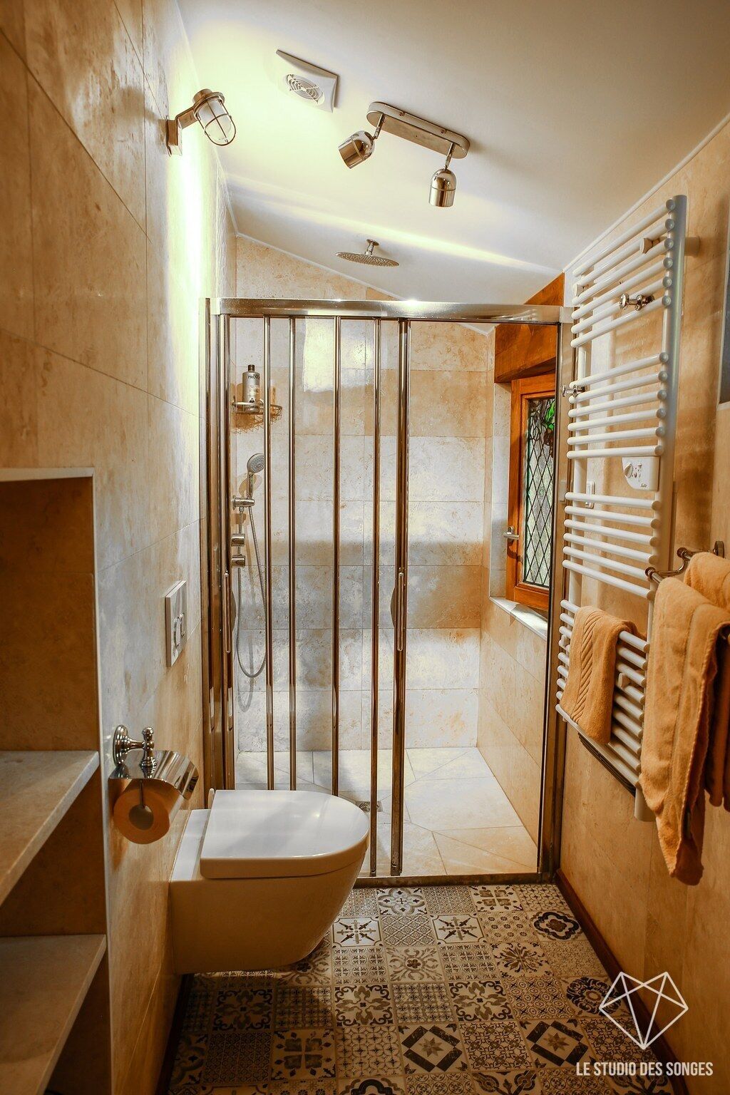 Un baño moderno con ducha envuelta en vidrio, inodoro y un perchero para toallas.