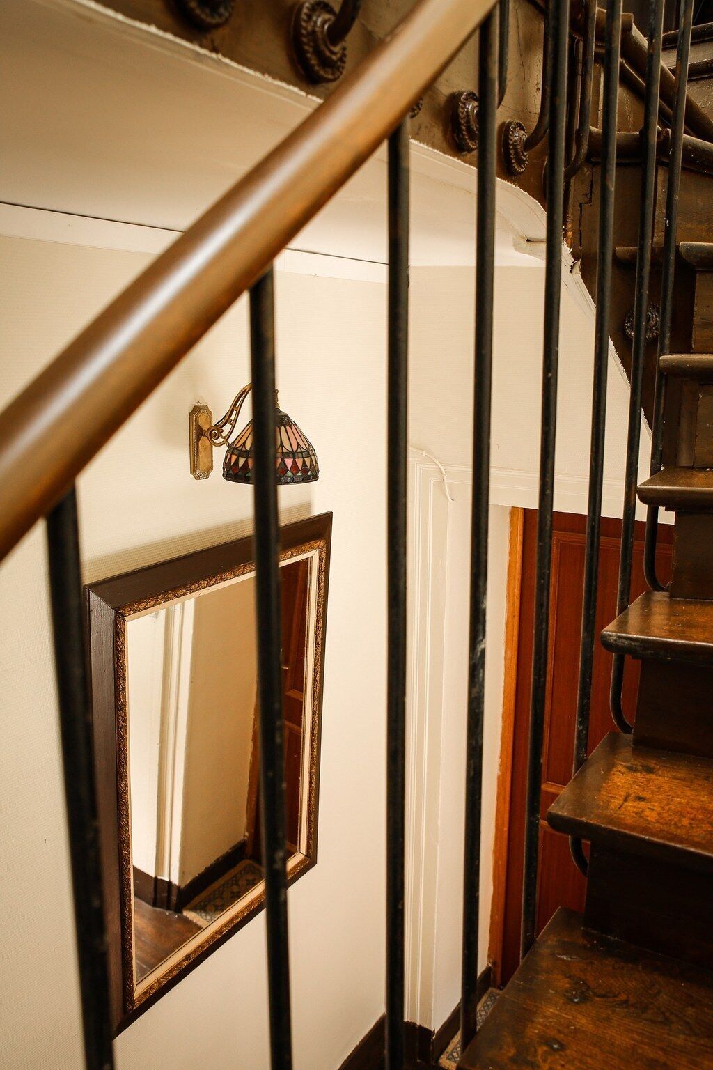 Una escalera con barandilla de madera y pasamanos metálico.