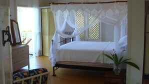 Een slaapkamer met een hemelbed, een dressoir, een stoel en een potplant.