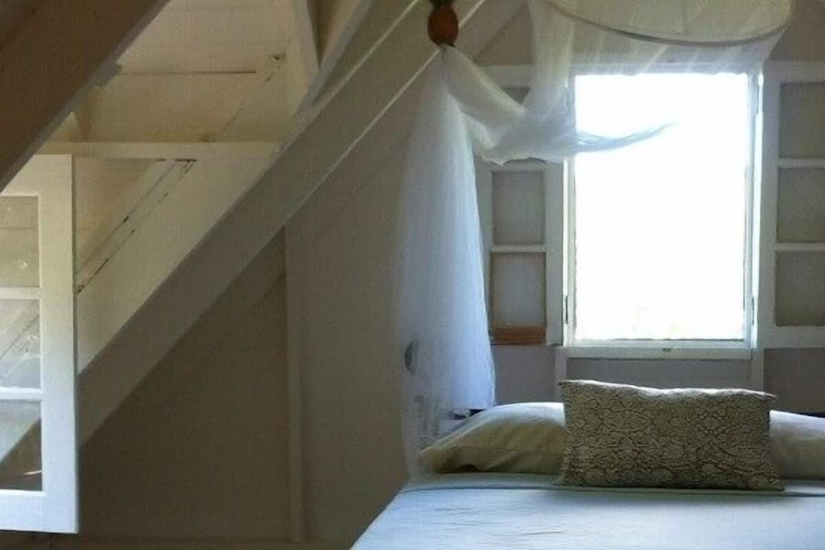 A bedroom with a bed, a window, and a nightstand with a lamp.