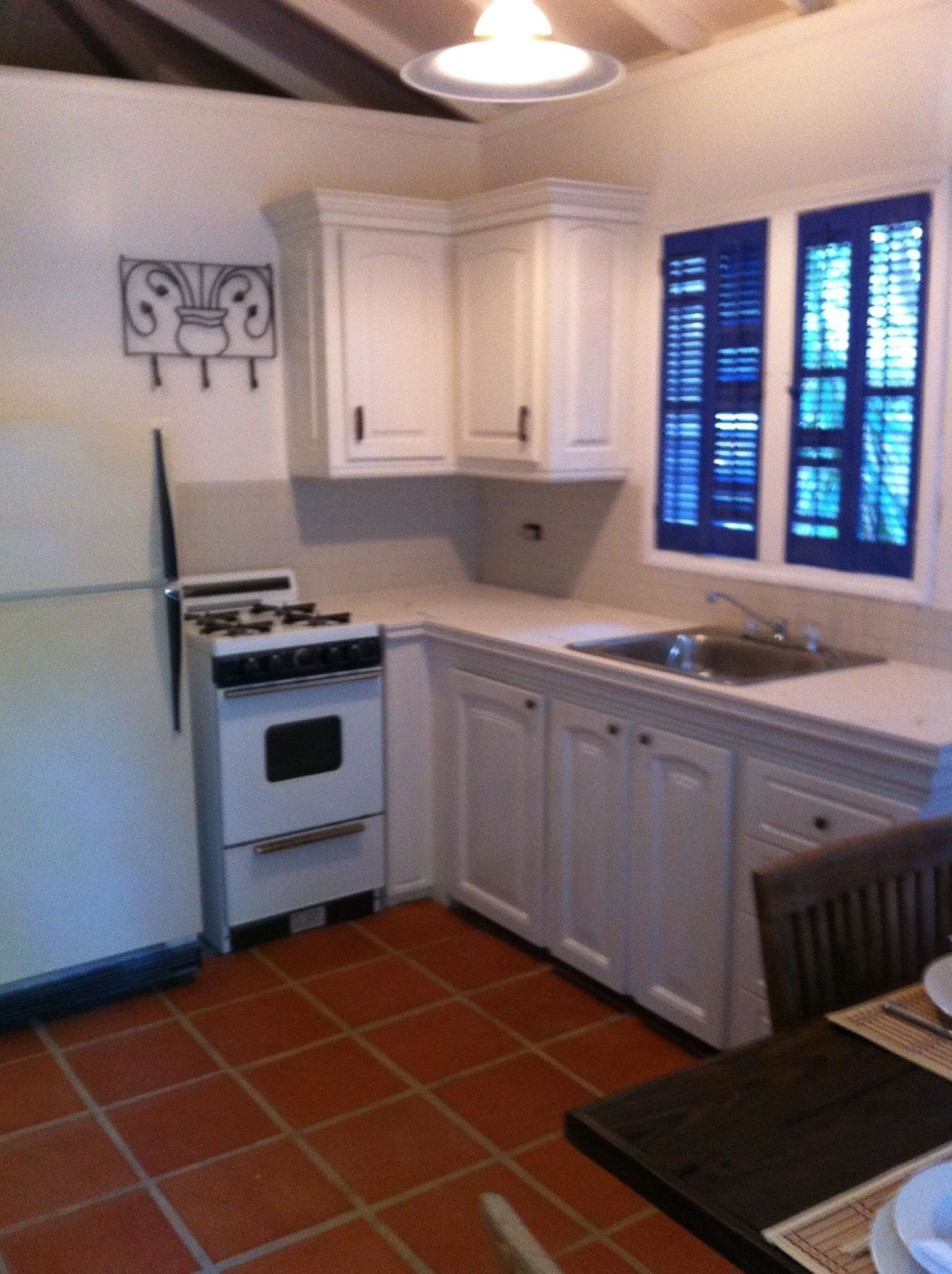 Una cocina compacta con gabinetes blancos, estufa y lavamanos.