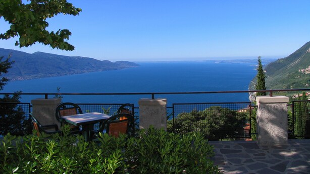 A terrace with a table and chairs overlooking a coastal view. - Hotel Residence La Rotonda (Tignale)