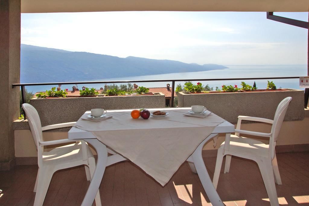 A balcony with a table set for two, overlooking a scenic view of mountains and a body of water.