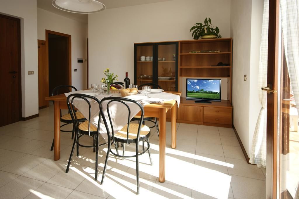 Een eetgedeelte met een houten tafel en stoelen, een televisie en een boekenplank.