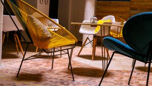 A room with a yellow woven chair, a blue chair, and a white table with yellow cushions. - Riad Belle Essaouira (Essaouira)
