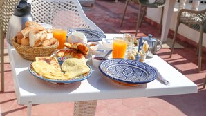 A breakfast table with bread, croissants, orange juice, and coffee. - Riad Belle Essaouira (Essaouira)