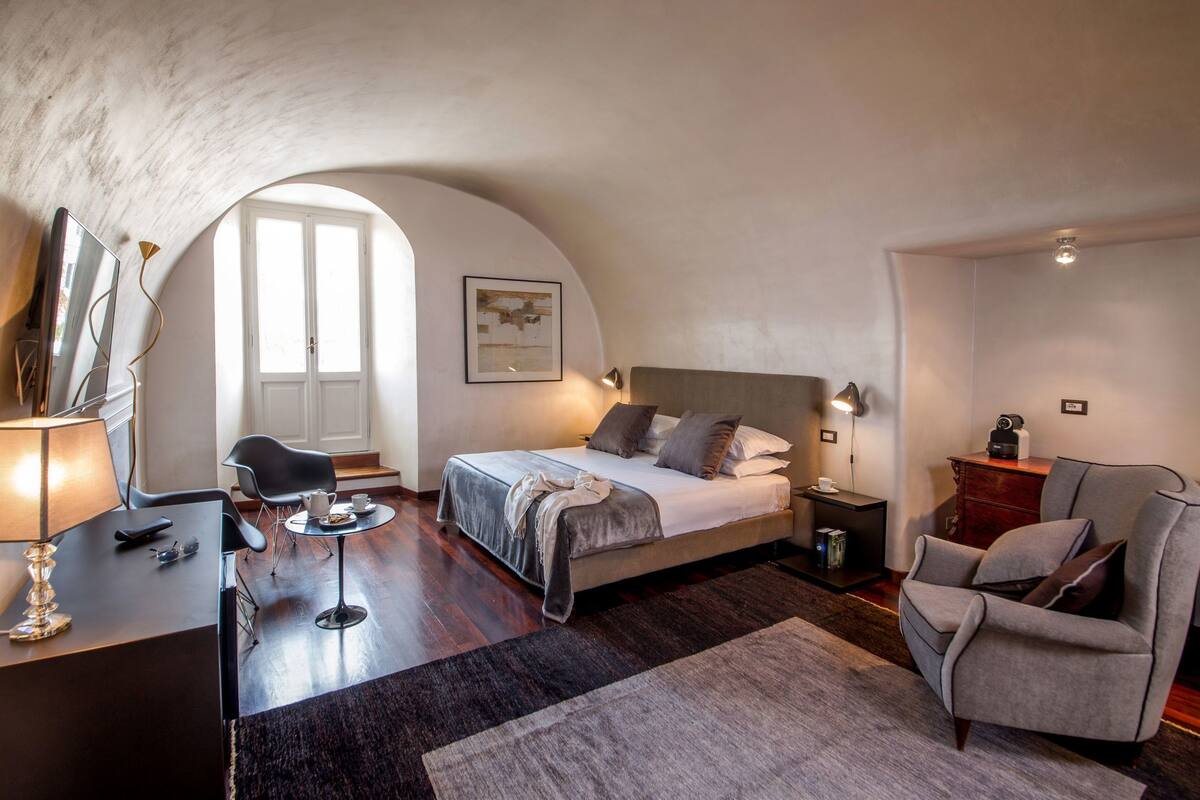 Un dormitorio con una cama grande, un escritorio, una silla y una mesita.