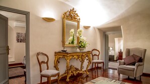 A room with a large ornate mirror, two chairs, a sofa, and a decorative console table with flowers. - Palazzo De Cupis (Rome)