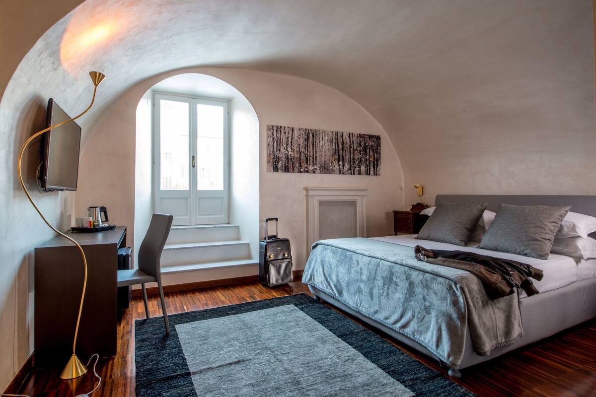 Un dormitorio con una cama grande, un escritorio con una silla, un televisor y una chimenea.