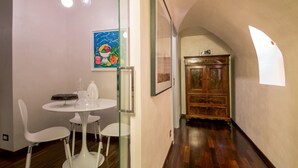 A modern dining area with a white table and chairs, a wooden cabinet, and a colorful painting on the wall. - Palazzo De Cupis (Rome)