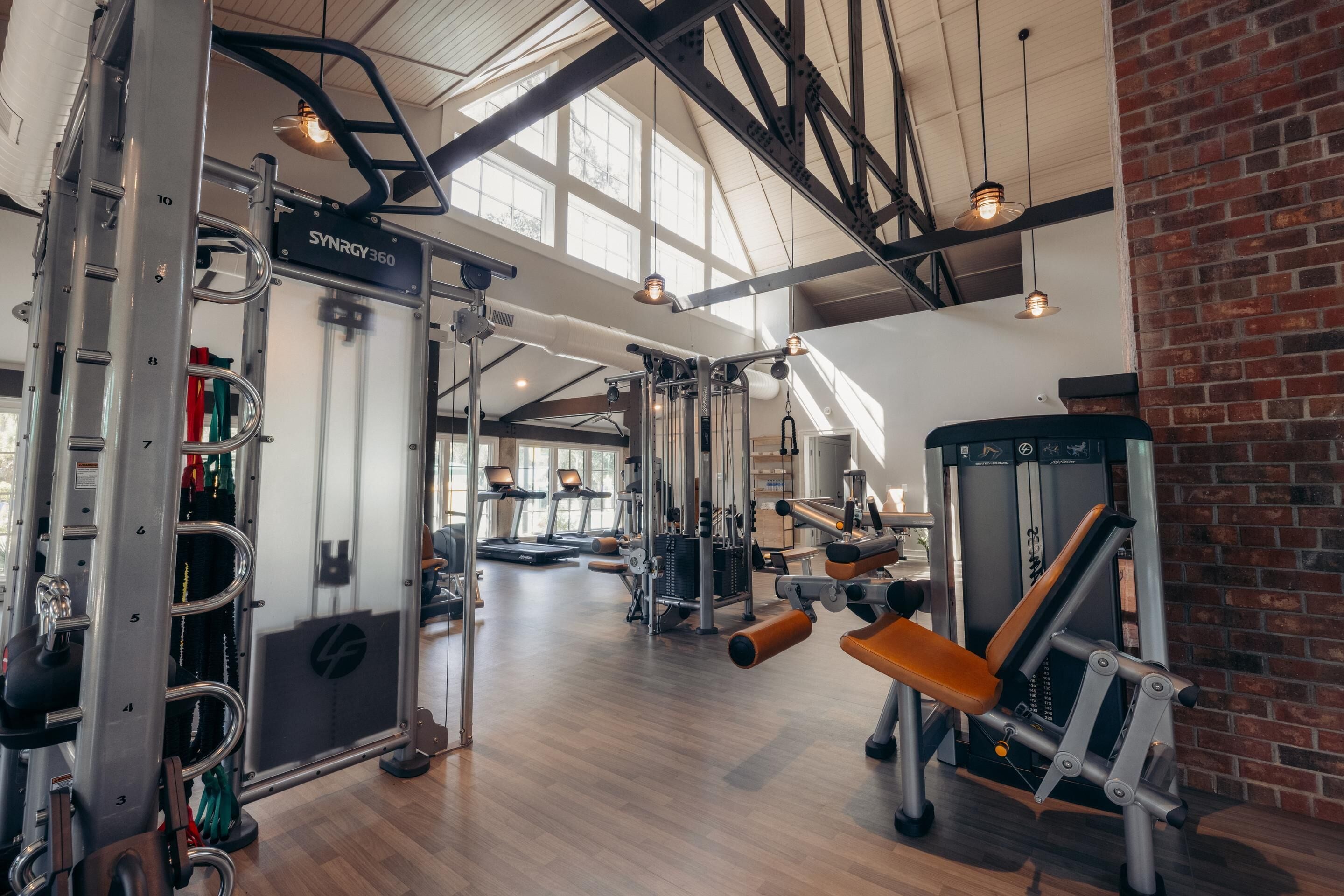 Une salle de sport équipée de divers appareils d’entraînement, notamment une machine Smith et des bancs de musculation.