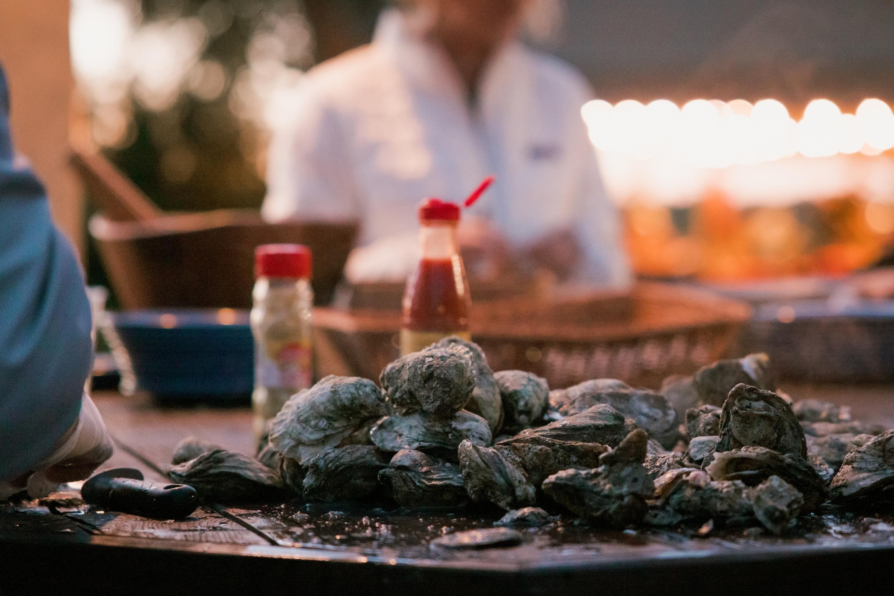 A table with oysters and a bottle of sauce.
