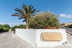 Une enseigne indiquant « Romanzá Villas », avec un palmier et des arbustes en arrière-plan.