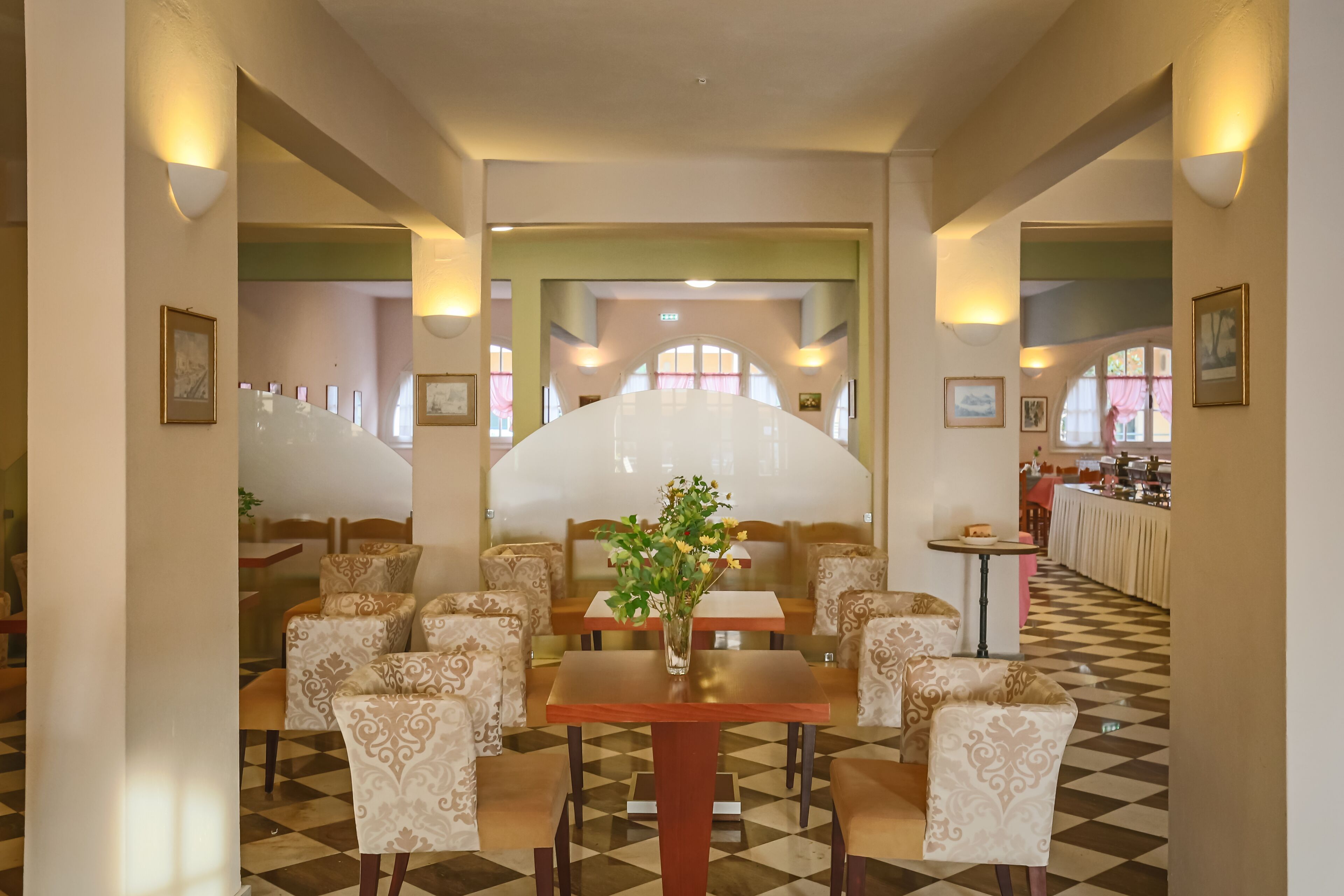 A dining area with patterned chairs, a central table with a vase, and a checkered floor.