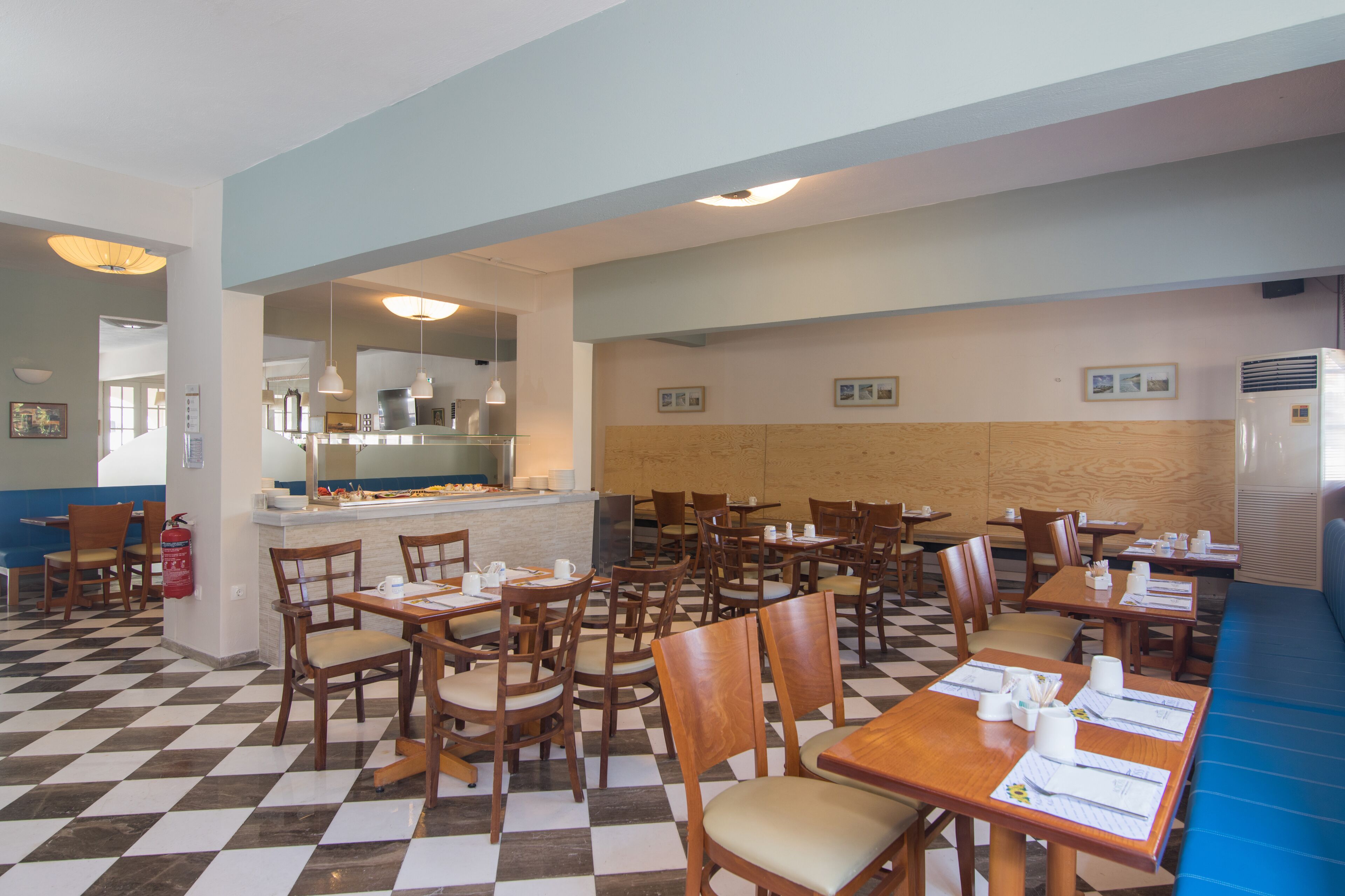 Un restaurant amb sòl d'escacs, taules i cadires de fusta i una zona de barra.