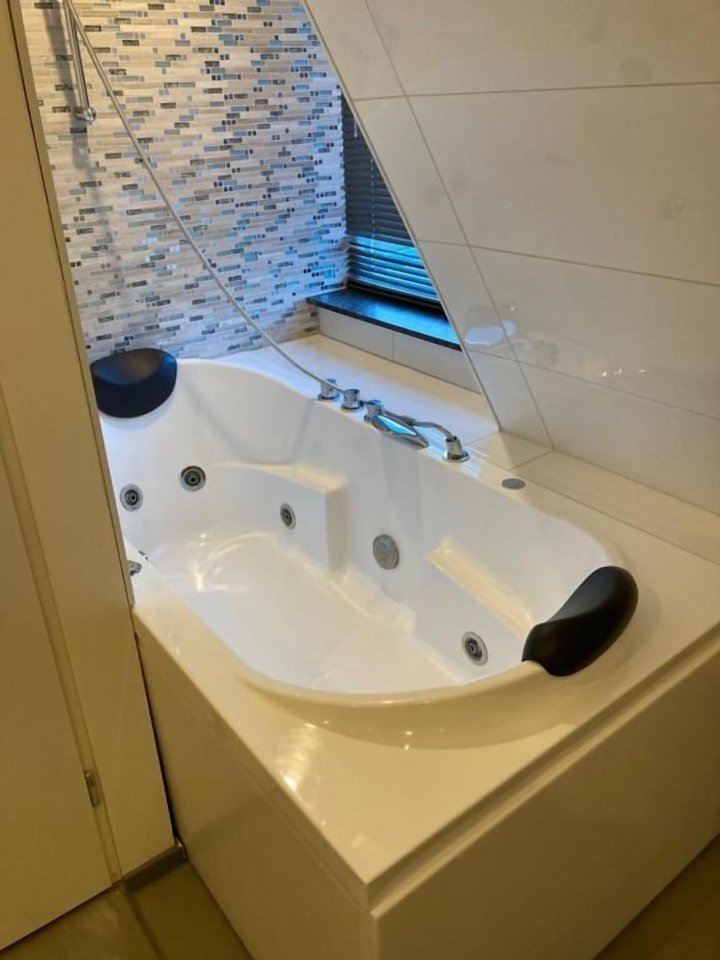 Een moderne badkamer met een vrijstaand bad, een douchecabine met glazen wanden en een betegelde muur.