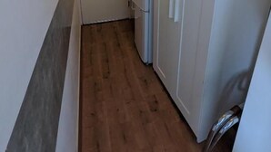 A narrow hallway with wooden flooring, white walls, and a closed door at the end. - Hotel Chao (Utrecht)
