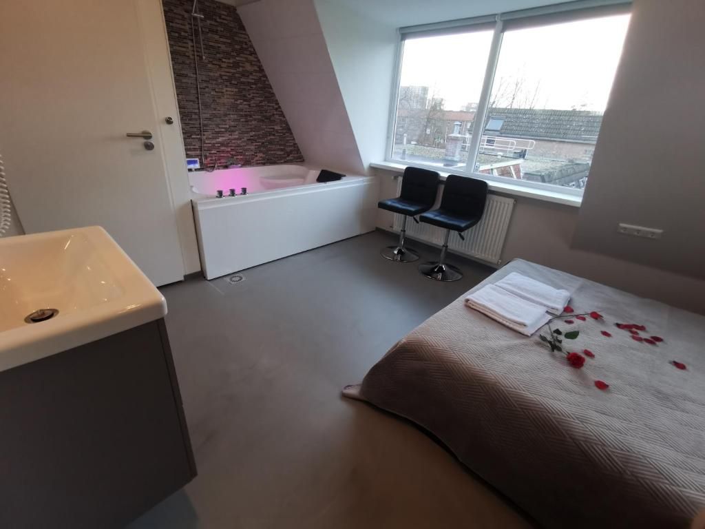 Ein modernes Badezimmer mit einer Badewanne, einem Waschbecken und zwei Stühlen in der Nähe eines Fensters.