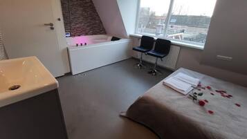 Ein modernes Badezimmer mit einer Badewanne, einem Waschbecken und zwei Stühlen in der Nähe eines Fensters.