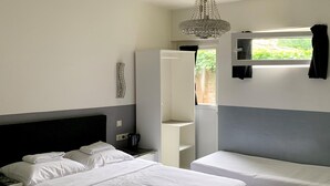 A hotel room with two beds, a wardrobe, a bedside table with a kettle, and a window with curtains. - Hotel Chao (Utrecht)