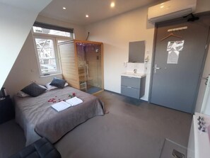 Un dormitorio con cama, armario, baño y ventana.